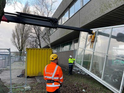 Kozijnen eruit halen voor hergebruik op slooplocatie ONS-gebouw in Schiedam